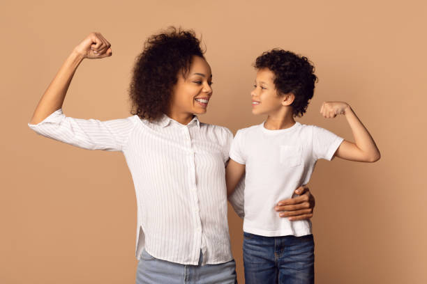 istock Woman and Boy Posing for Picture, Showing Biceps 2164536682