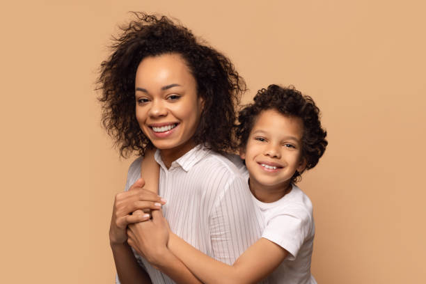 istock Smiling Mother Embracing Her Young Son Against Warm Beige Background 2164536795