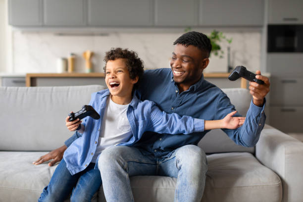 istock Black father and son laughing while playing video games together 2164536874
