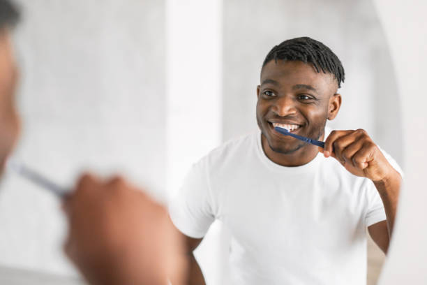 istock Handsome African American millennial guy brushing teeth in modern bathroom 2164537098