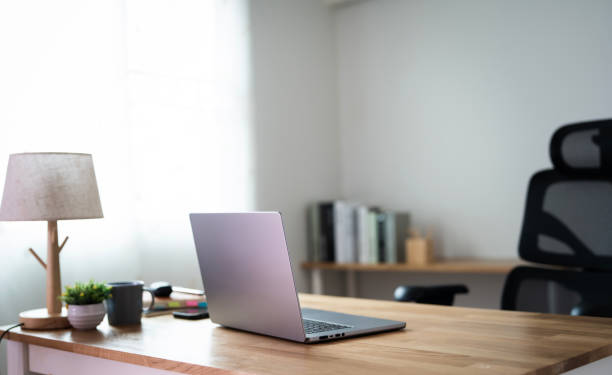 Laptop computer with opened lid on table in modern home office room. Creative workspace background concept.