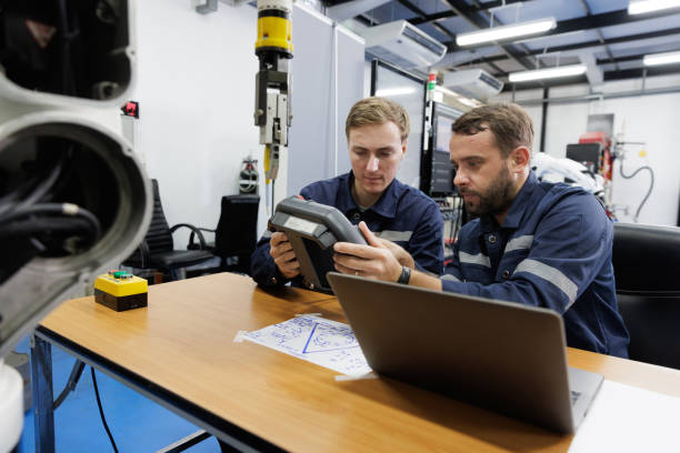 istock Two engineer sits in a research lab analyzing the performance of a robotic arm. 2164548587