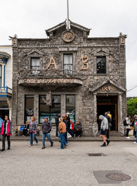Skagway, Alaska - July 3, 2024: People in front of the Visitor Information Center for the Skagway Convention and Visitors Bureau. Built in 1899, the Arctic Brotherhood Hall has over 8000 pieces of driftwood covering it according to their website.