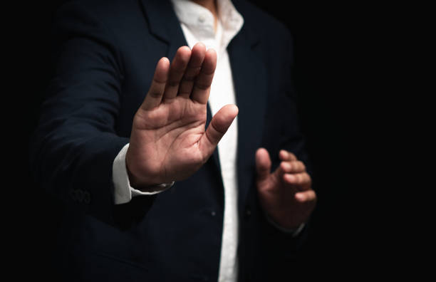 istock Businessman shows a stop gesture while standing on a black background. 2164553288