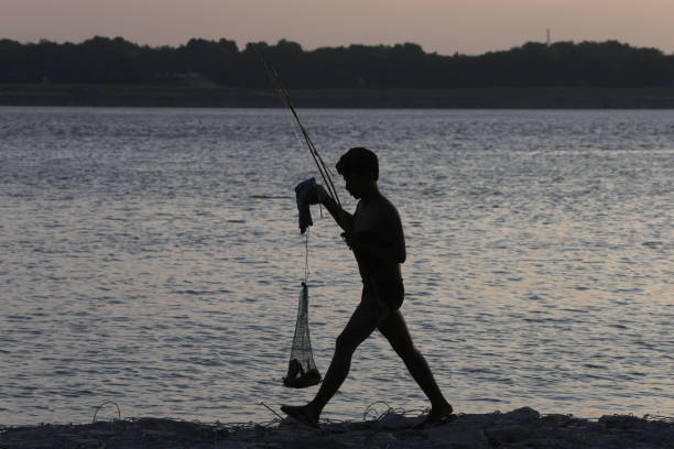 A fishermen busy in fishing in the River  Ganga after water level of river rose during the sunset in Prayagraj, India.