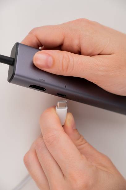 istock A woman inserts a white Type C cable into a black port. 2164562705