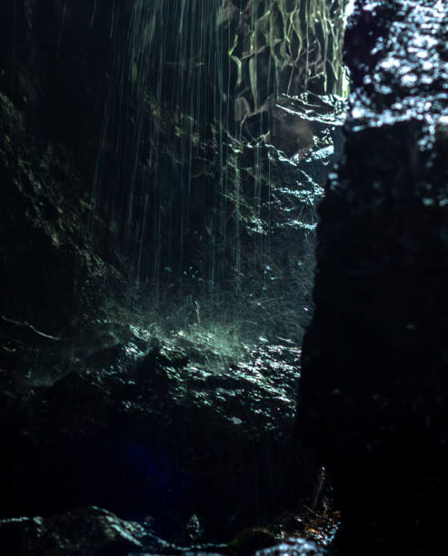 istock Dark abstraction with rain falling on a rock and droplets in a ray of light. 2164568118