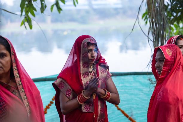 Ghaziabad, Uttar Pradesh, India - November 2023: Chhath Puja, Indian hindu woman devotee performing rituals of chhath puja with standing in river.