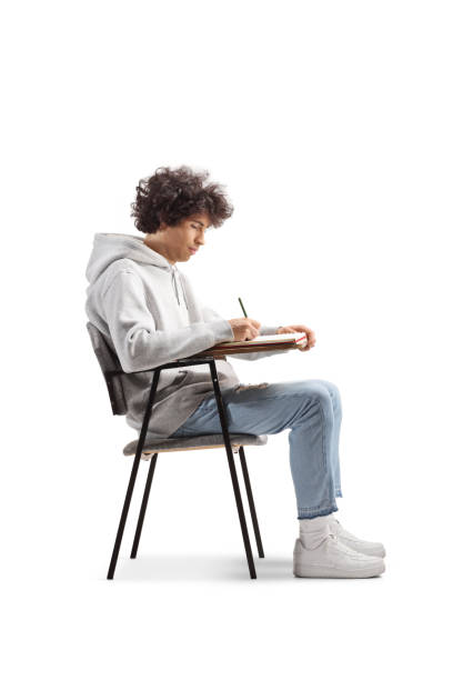 Guy sitting in a school chair and writing isolated on white background