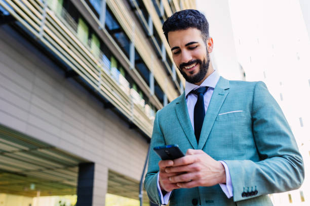 istock Businessman in formal suit using cellphone standing outside building office 2164572758