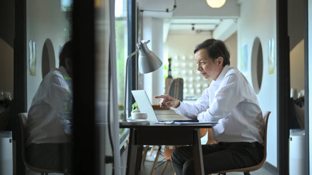 istock Smiling middle age businessman in white shirt working in a modern office environment 2164576056