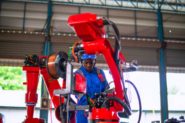 Blue collar worker is set up robot arm at factory. Engineering and technology concept.