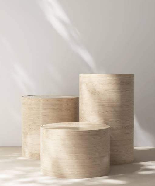 istock Three modern, minimal cylinder wooden pedestal table podium in dapple sunlight, shadow on white wall, beige floor 2164580324