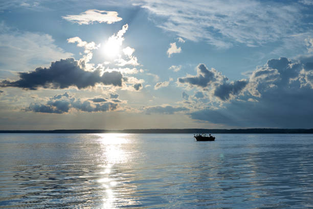 A boat sails down the river against a blue sky with clouds