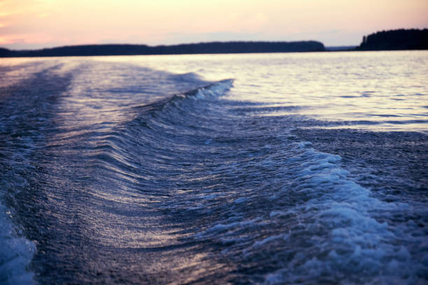 a big wave from a boat on the river against a pink sunset on a summer evening