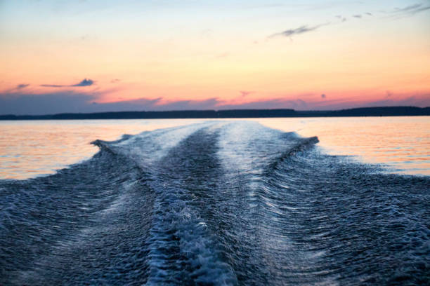 a big wave from a boat on the river against a pink sunset on a summer evening