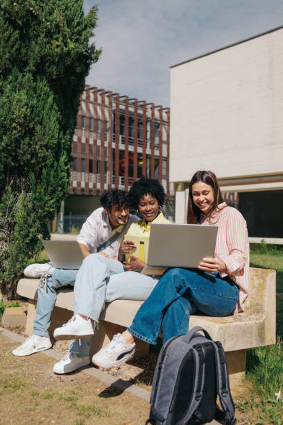 istock Multiethnic student friends studying together working on laptops sitting in bench at college campus. 2164587336