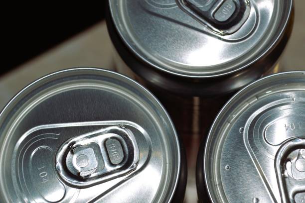 istock Three aluminum cans with pull tabs, focusing on the top part where the cans are sealed and the tabs are attached. It highlights the metallic texture and the circular lids of the cans. 2164588120