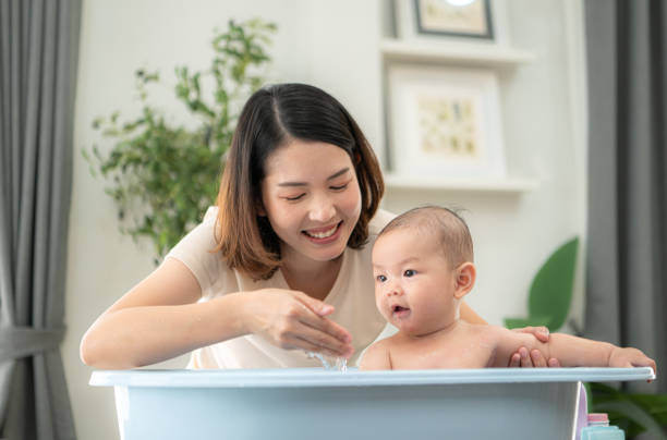 istock A tiny child enjoys taking a bath in a baby bathtub with mom 2164588374