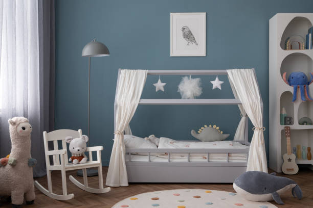 istock Creative composition of child room interior with mock up poster frame, cozy bed, stylish rack, blue wall, rack with toys, plush lama, gray lamp, guitar and personal accessories. Home decor. Template. 2164594775