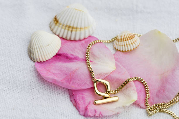 istock Gold link necklace on rose petals and seashells 2164599154