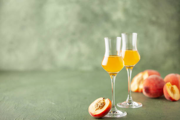 istock Peach liqueur in grappas glasses and fresh peaches on the table. Copy space 2164600909