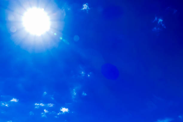 The sun is shining brightly in the sky, casting a warm glow on the blue clouds. Concept of happiness and positivity, as the bright sun and clear blue sky create a beautiful and uplifting scene