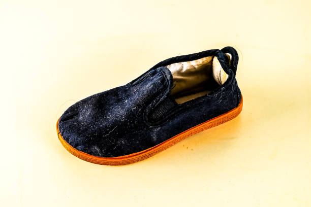 A black shoe with a white sole. The shoe is worn and dirty