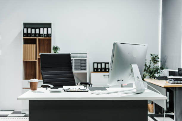 istock A modern, white-colored business office with a wooden desk, calculator, desktop computer, and a black leather chair. The executive office features private office furniture for the chief of staff. 2164601992