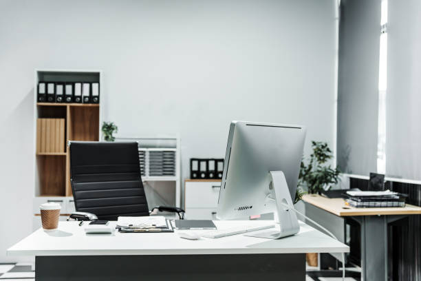 istock A modern, white-colored business office with a wooden desk, calculator, desktop computer, and a black leather chair. The executive office features private office furniture for the chief of staff. 2164601998