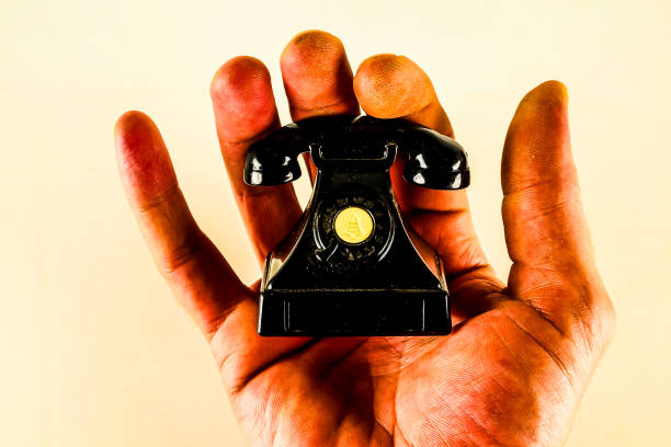 A hand holding a small black phone with the number A on it
