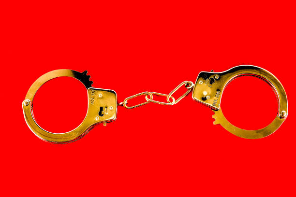 istock Two handcuffs are shown on a red background 2164602898