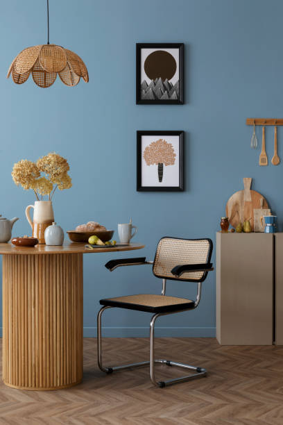 istock Warm and cozy dining room and kitchen interior with mock up poster frame, round table, rattan chair, beige commode, blue wall, vase with flowers and kitchen accessories. Home decor. Template. 2164604864