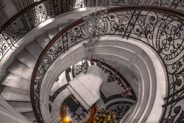 The intricate spiral staircase features a winding design that leads up to a glowing light at the top, showcasing the architectural beauty of a historic building in Prague.