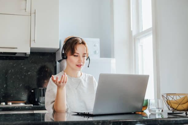 istock Remote work at home. Woman in headset working on Laptop at Kitchen Table in tiny flat. Student has online classes. Manager has video meeting. Customer support operator in telemarketing service 2164610059