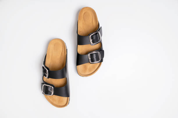 istock Black leather sandals with cork soles on a white background, top view flat lay. Trendy fashionable summer clogs, unisex sandals. Minimalism style 2164610098