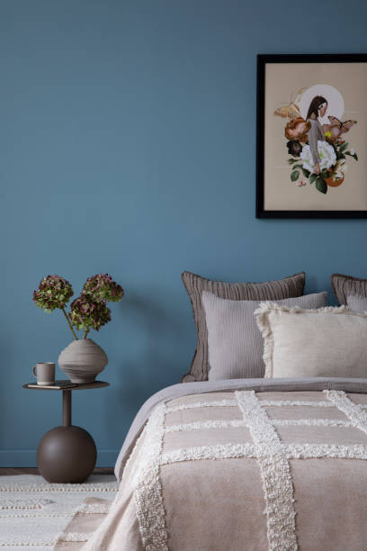 istock Minimalistic composition of cozy bedroom interior with mock up poster frame, bed, gray bedding, stylish bedside table, vase with flowers, blue wall and personal accessories. Home decor. Template. 2164615009
