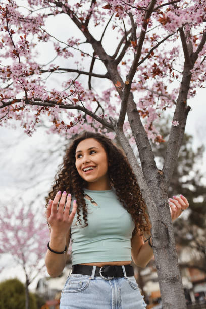 istock Female Spending The Day In Park Among Pink Trees 2164617996