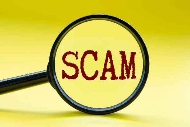 istock Magnifying glass focusing on SCAM text on yellow cover background. Cyber security concept 2164626765