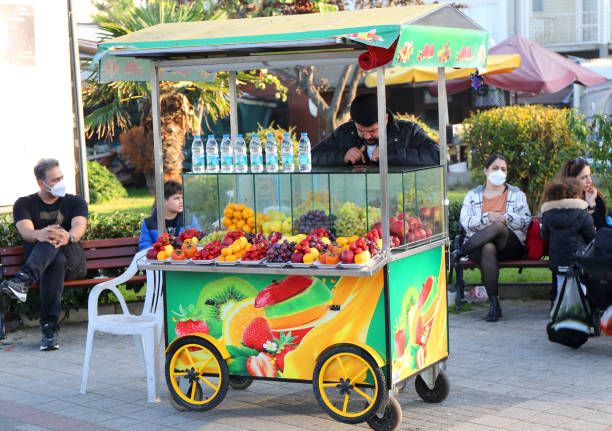 Fruit cart with colorful delicious Fruits and People Buyukada, Istanbul, Turkey-November 05,2021:Fruit cart with colorful delicious Fruits and Unidentified People sitting around it fruit cart vendor stock pictures, royalty-free photos & images