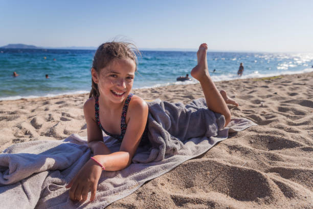 Cheerful teenage girl sunbathing Happy girl smiling when resting on a beach towel girls laying on beach stock pictures, royalty-free photos & images