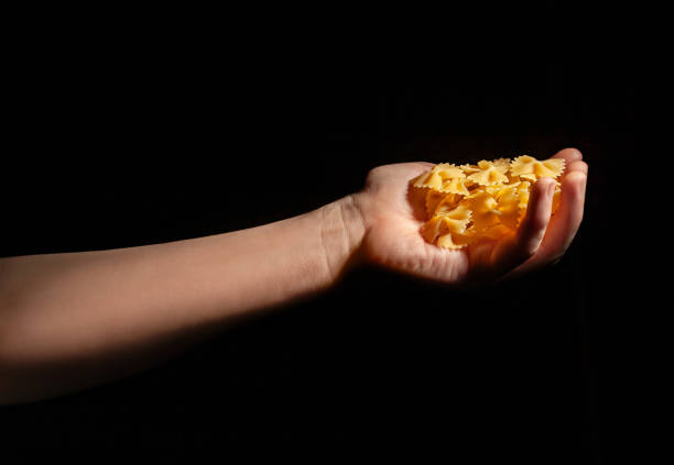 istock pasta farfalle in hand on black 2164631179