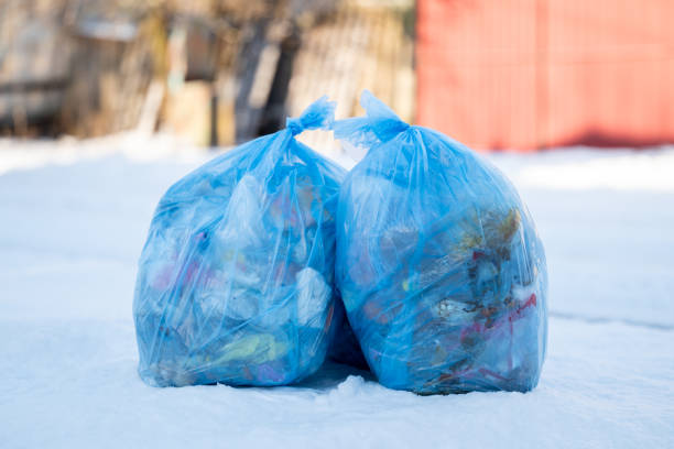 istock Two blue plastic bags full of garbage on snow, close up 2164633204