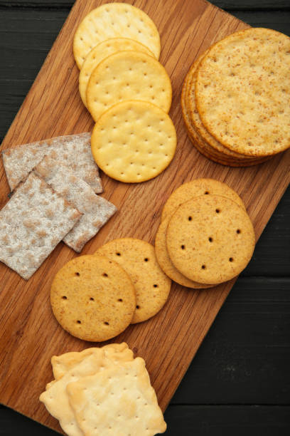 istock Different crackers on cutting board on black wooden background. Vertical photo 2164634812