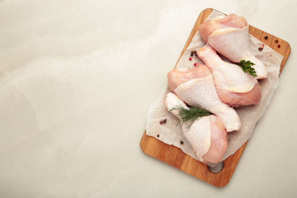 istock Raw chicken drumsticks with spices on cutting board on light background. Top view. Free space for your text. 2164635087