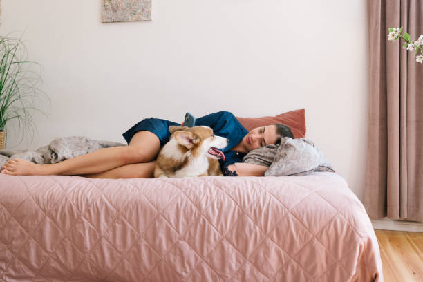 istock lazy morning: young woman waking up in bed with her dog 2164635593