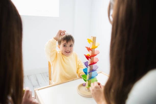 istock Happy boy with attention deficit hyperactivity disorder playing with women 2164637500