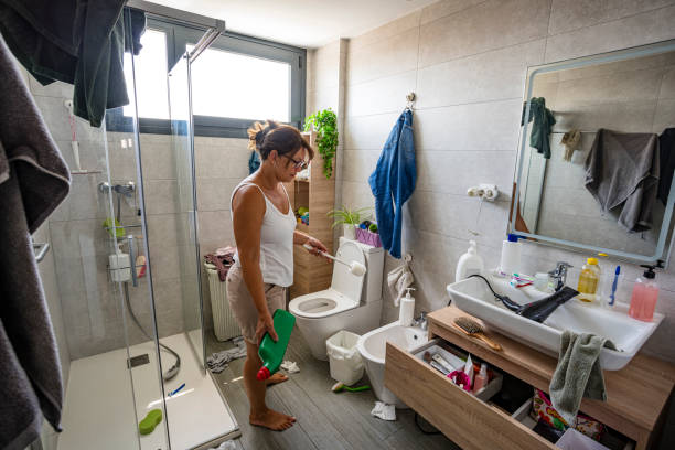istock Woman standing her cluttered and dirty bathroom 2164647061