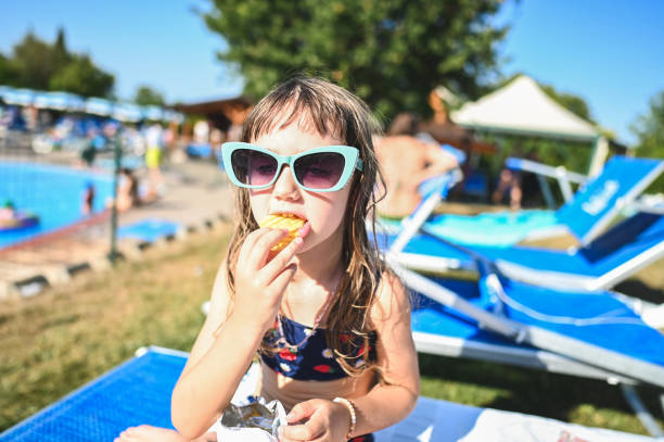 Cute little girl eating potatoes chips.