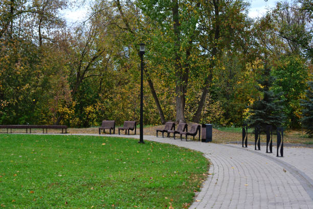 istock a park with benches and a green lawn and a pathway 2164651309